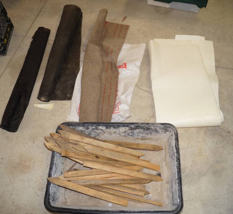 lot 1205 image: Lot of Flat Cork Material, 2 rolls of weed barrier, white cushion material, wooden stakes and a material mixing tray