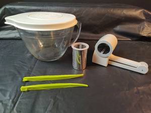 lot 301 image: The Pampered Chef Rotary Grater with Attachment, Measuring Bowl with Lid and Plastic Fruit Peelers