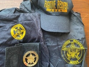 lot 24 image: Fugitive Recovery Agent Gear - Hat, Shirt, Badge and Jacket, all in a Black Bag