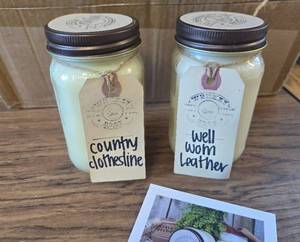 lot 6995 image: 2 Pack Whiskey Boat Candles, Country Clothesline & Well-Worn Leather, 16oz