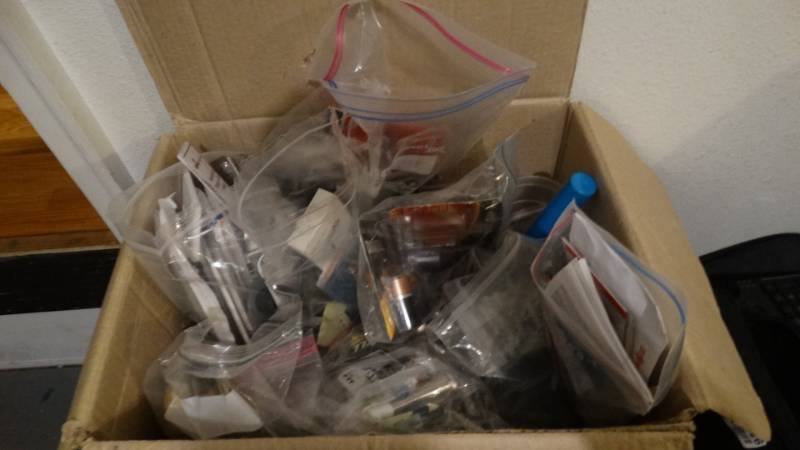 lot 1881 image: Box full of batteries, outlet covers, anchors, pens, door stoppers, outlets and more.