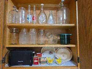 lot 271 image: Contents of Cabinet- Quart Canning Jars, Unique Bottles, Dishes, Corn Cob Holders, Spice Tins, and Toaster