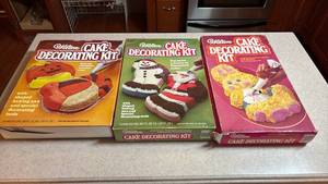 lot 115 image: Vintage 80s Wilton Cake Decorating Kits - Holiday Themed - Christmas, Thanksgiving, and Easter - all appear new in open boxes.