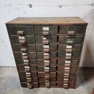 lot 4 image: Industrial Metal 27-Drawer Storage Cabinet (has patina). Missing most of the metal cover that separates each drawer column. Has a little give in integrity (bends slightly if moving by 1 corner) but fairly stable if you dont plan to move it around