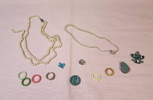 lot 94 image: Broken jewelry and charms, does include one intact gold tone ring (which could also be strung on a chain as a pendant).  Eagle ring intact but band is very bent.