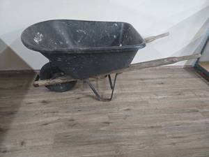 lot 64 image: Black Wheelbarrow with Wooden Handles (bucket is cracked and tire need air or replaced)