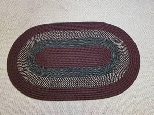 lot 235 image: Burgundy and Navy Braided Oval Area Rug Needs a few stiches.