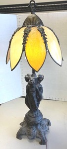 Antique Tiffany-style table lamp featuring a figural metal base depicting sculpted female figures and a floral-shaped slag glass shade