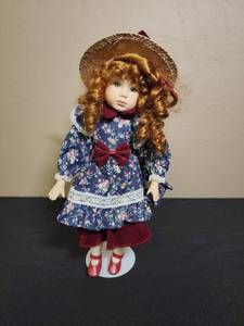 lot 204 image: Porcelain Doll in Floral Dress with Straw Hat on a stand - has rhinestone accents on the lace and hat