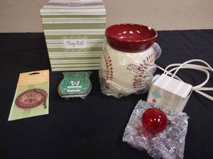 lot 322 image: Scentsy Play Ball Baseball Stitches Electric Wax Warmer (has small chip on the edge of bowl), open package of wax (2 squares left), a car air freshener, and a red Scentsy light bulb