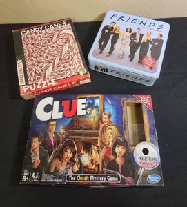 lot 439 image: Game Collection Bundle - Friends Trivia in Tin Box, Clue, and Candy Canes Puzzle - no guarantees of all pieces but boxes are fully intact