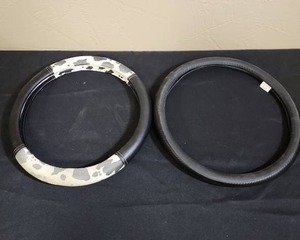 lot 542 image: Two Steering Wheel Covers - one has cow print, the other is black - both very good condition