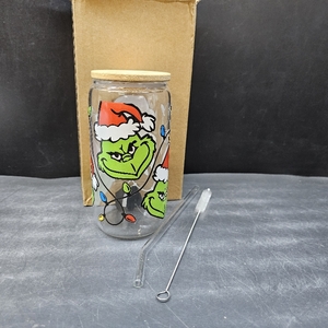 lot 4117 image: 16 oz Grinch-themed glass tumbler, likely a Libbey-style glass can, featuring a bamboo lid, a glass straw, and a straw cleaning brush.