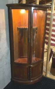 lot 300 image: Curved front glass and wood top lit locking gun cabinet with key 75 x 43 x 13 in IN BASEMENT