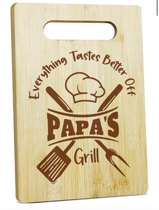 lot 3116 image: Dad Cutting Board - Everything Tastes Better Off Papa - Engraved Bamboo Cooking Board Gift Set for Papa, Stepfather, Godfather with 3 wood spoons - Retail $0