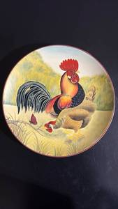 lot 284 image: Decorative plate featuring a rooster and hen design. Approximately 10 inches diameter