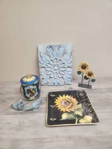 lot 546 image: Decorative Home Collection with Wall Art, Sunflower Plate, Vintage Tin with handle, small rooster figurines (one is broken on top), and a metal sunflower sculpture