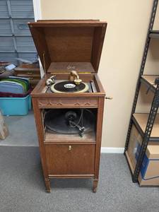 lot 5 image: c.1912 Antique Edison Diamond Disc Phonograph in working conditon, includes full cabinet of discs. May need slight maintenance  oiled. Measures approx 22W w handle on side, 25D x 44H. On wheels but they are rusty and need replaced.