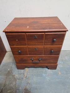 lot 18 image: Wood laminate night stand.  Matches the one in lot 17 and the dresser in lot 19. Some scratches on the top and glitter stuck on the top and in the top drawer. Missing one Knob 23W x 15.75D x 26H
