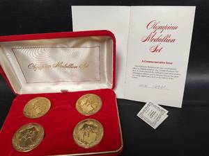 lot 591 image: Vintage Olympic Medallion Set - Four Gold-Toned Sports Medals with Lifetime Guarantee Cert and Documentation