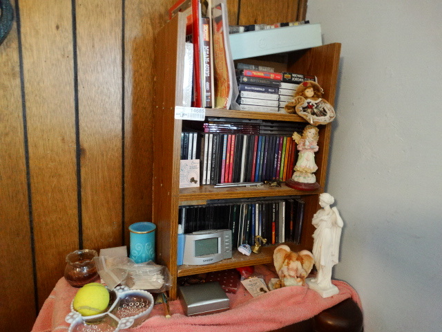 lot 14685 image: Cds, figurines, candles, cassette tapes, small wooden shelf.