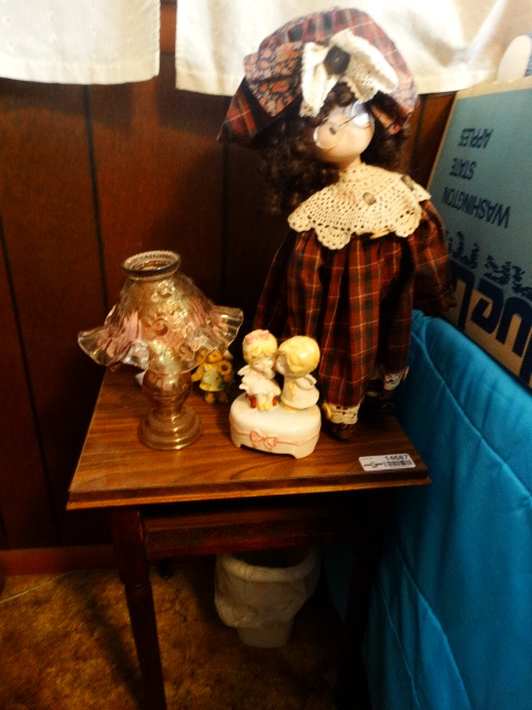 lot 14687 image: Small wooden night stand, candle decor, doll.