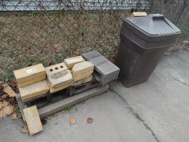 lot 14878 image: Bricks and a trash can with a lid.