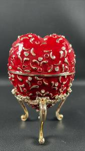 lot 117 image: Wallace Musical Red Enamel Faberge Style Heart Shaped Egg with Doves and Roses