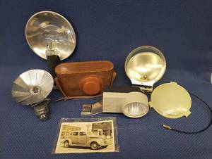 lot 76 image: Vintage Camera Light Meter, Flash Attachments, Leather Camera Case, and 1930s Postcard
