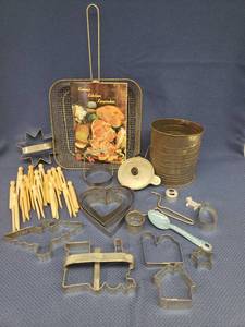 lot 83 image: Vintage Kitchen Collctibles Fry Basket, Hand Sifter 6.25in T, BisquitCookie Cutters, Kansas Kitchen Keepsakes Cook Book, Slicer, Egg Poacher, Enamelware Spoon and Old Wooden Clothespins