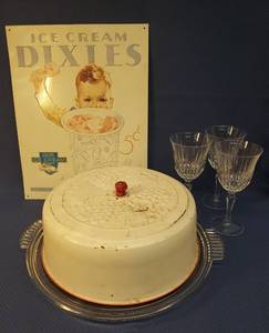 lot 158 image: Vintage Ice Cream Advertisement Metal Sign 12.5in W x 16in T, Vintage Anchor Hocking Manhattan Pattern Cake Plate 15.75in W with RedWhite Enamel Embossed Metal Cake Dome with Red Wood Handle & Fruit Design, and 3 Crystal Wine Goblets