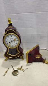 lot 2013 image: Schmid mantel clock 15 inches tall featuring a burgundy lacquer case finial needs repaired, with matching shelf