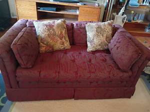 lot 917 image: Maroon Colored Love Seat. With Throw Pillows.  Has a leaf pattern.   25 x 58 x 34