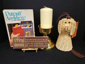 lot 45 image: Woven Rattan Pig Bell Chime with Hanging Cord & Original Tag, NIP A Friend Plaque, Gold Metal Display Easel, Putputt Anywhere Take-A-Long Book Light, and Large Heavy Brass Candle StandHolder 6in T x 5.25in W with Pillar Candle
