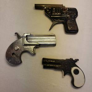lot 111 image: Vintage Toy Cap Guns One 1950s Black Pressed Steel Double Barrel Piston, One 1970s Silver Cast Metal Derringer - missing Handle Casings - Made in USA,  and One 1960s BlackWhite Plastic Pressed Design Derringer