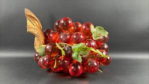 lot 14 image: Vintage large mid-century modern Lucite grape cluster sculpture features large, amber-orange acrylic grapes mounted on a piece of driftwood. Approximately 12 inches long.