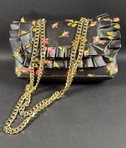 lot 32 image: Never Used Betsey Johnson $ Ruffle Convertible Bag features a floral ditsy print with a prominent ruffled bow detail.