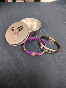 lot 62012 image: Kobe Bryant commemorative set features a purple and yellow Mamba silicone wristband and a black leather bracelet with a metal 24 plate