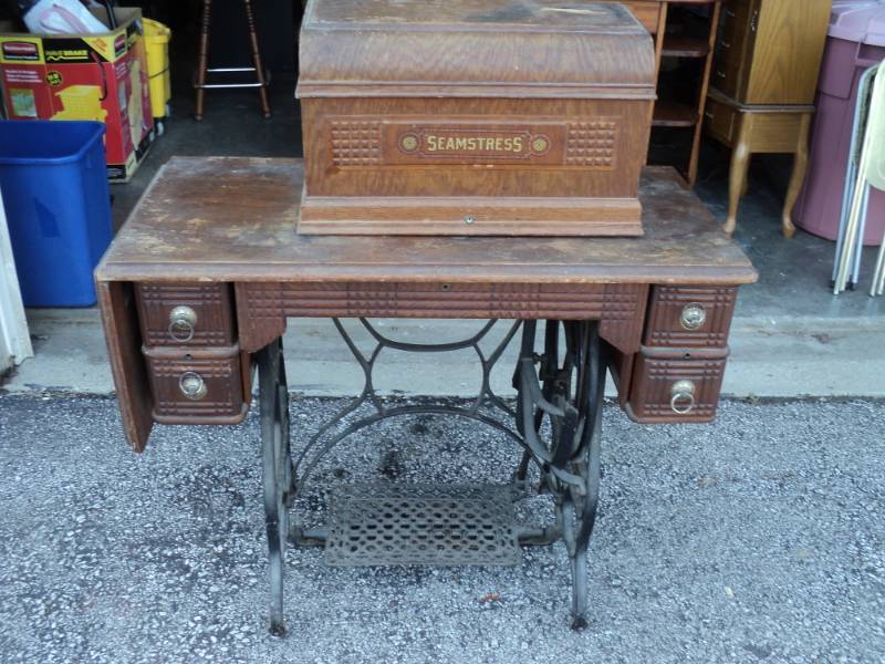 lot 4462 image: Seamstress Sewing Machine with Wooden Coffin style Cover, wooden & metal Table, book and other pieces.