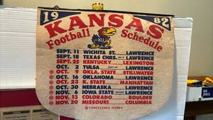 lot 1315 image: Kansas Jayhawks 1982 Football Schedule PennantLarge framed newspaper (cracked glass) and yearbook