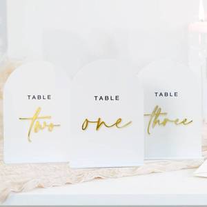 lot 662 image: White Arched Wedding Table Numbers 1-10 with Stands, 5x7 Inch White Acrylic Arch Sign with Gold Numbers, Acrylic Table Numbers for Wedding Reception - Retail $27