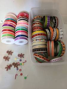 lot 1415 image: Rolls of ribbon, ribbon wrapped canning jar lids, small gingerbread men decor.