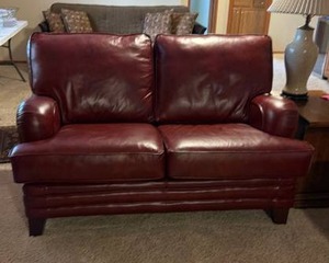 lot 901 image: Burgundy leather loveseat sofa 36 x 60 x 36 in (located in basement)