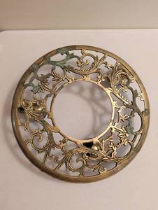 lot 1715 image: Round Gold-Tone Pierced Trivet with Scroll Leaf Design and Rolling Casters. One bent wheel post. 11