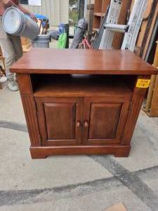 lot 25158 image: Wooden TV stand with open upper shelf and a lower two-door cabinet with raised panel doors