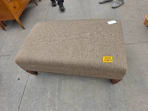 lot 25156 image: Rectangular upholstered ottoman covered in a textured brown fabric and set on traditional dark turned wood bun feet