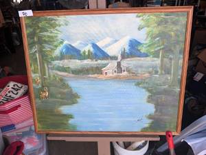 lot 70 image: Vintage mid-century landscape oil painting featuring a river, cabin, and snowy mountain peaks framed in wood