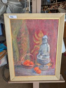 lot 76 image: Framed still life oil painting featuring a small Buddha figurine, a basket of fruit, and scattered oranges against a reddish, textured background.