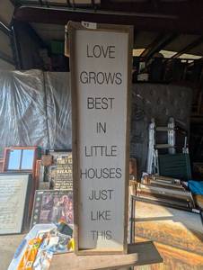 lot 88 image: Vertical rustic wooden wall sign featuring the phrase Love Grows Best in Little Houses Just Like This in dark block lettering.