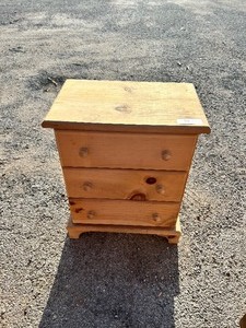 lot 94 image: Small, three-drawer pine nightstand with wooden knob handles and a light natural wood finish